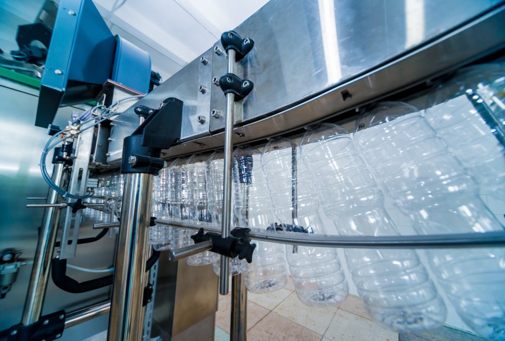 image shows an automated bottling line, likely for a liquid such as water or oil